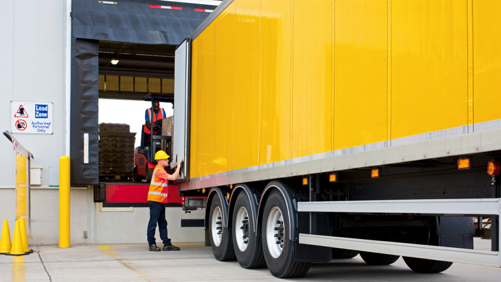 Workers loading a yellow semi-truck at a dock, highlighting Trailer Spotting and Yard Shuttling efficiency
